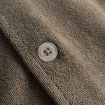 Close up of white pearl button on a white and brown short sleeve shirt.