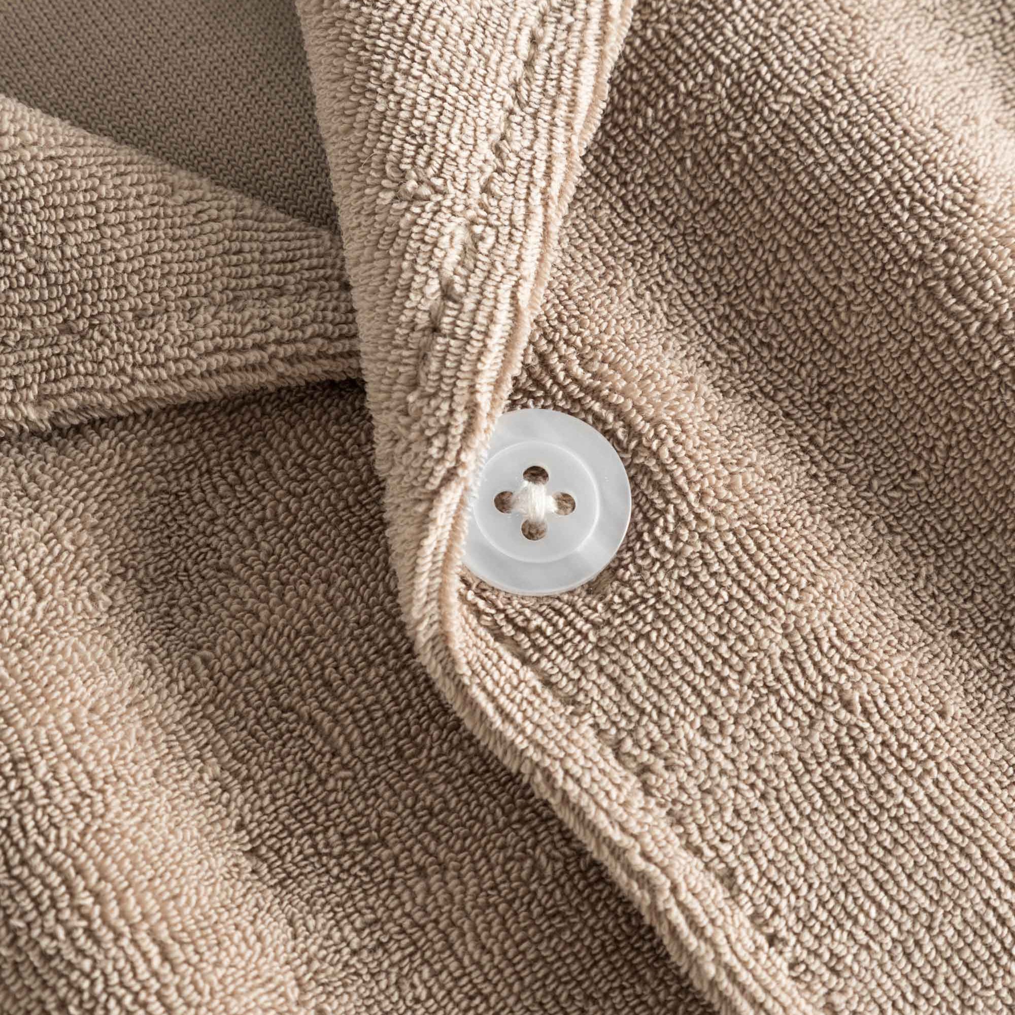 Close up on white pearl button on a light brown, short sleeve, cropped shirt