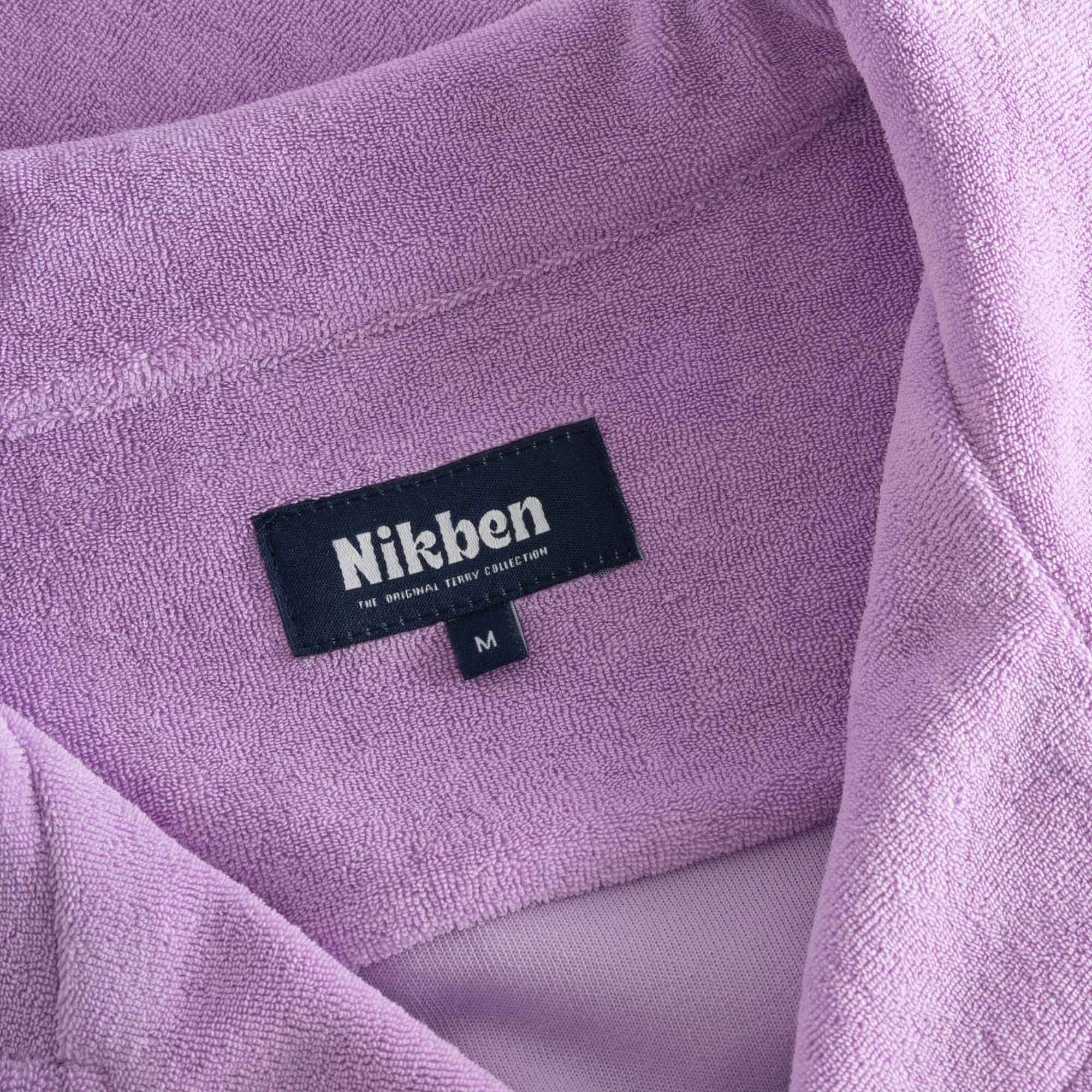 Close up on open collar and tag on a purple, short sleeve, cropped shirt