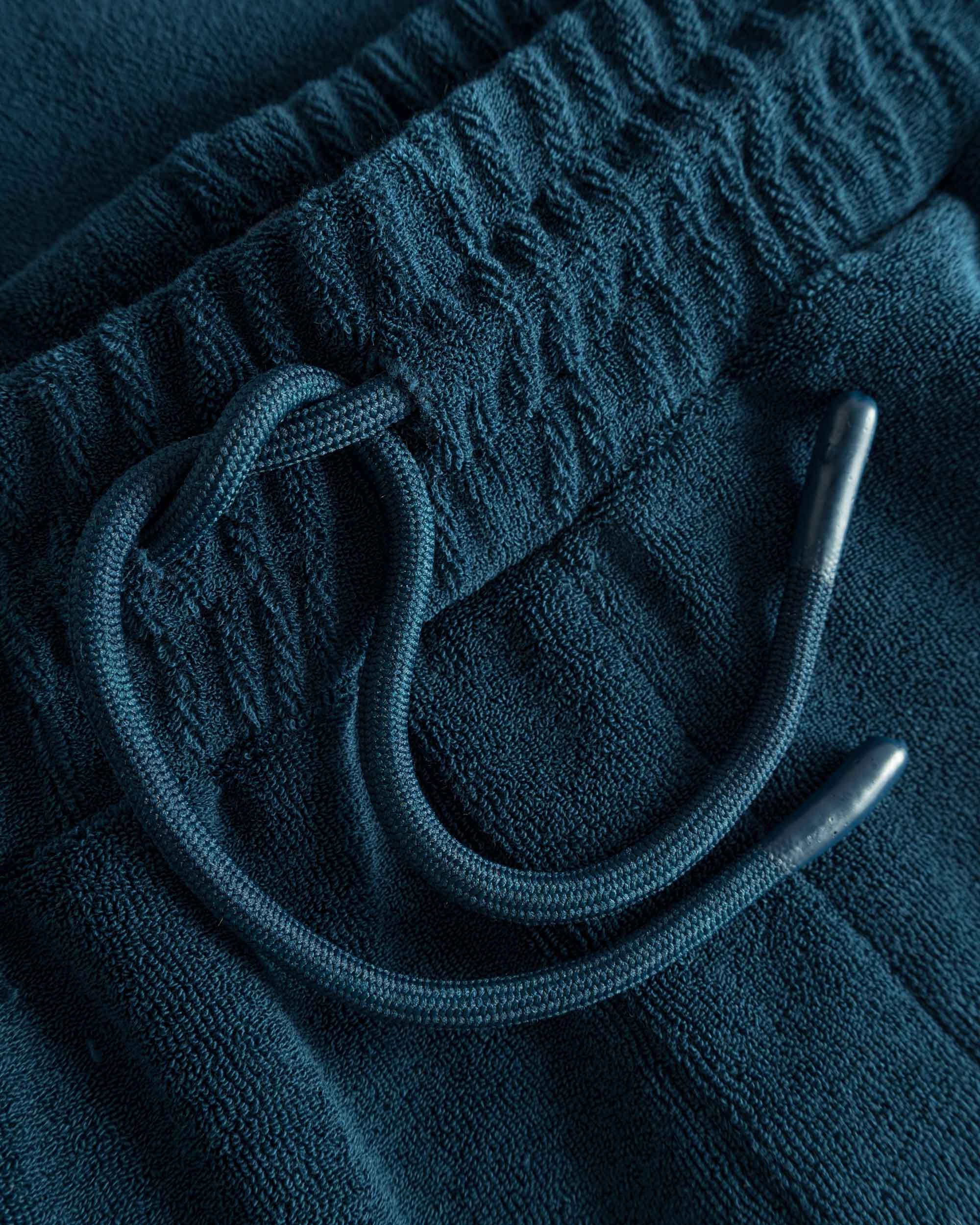 Close up on drawstring on navy colored low cut shorts in terry toweling fabric