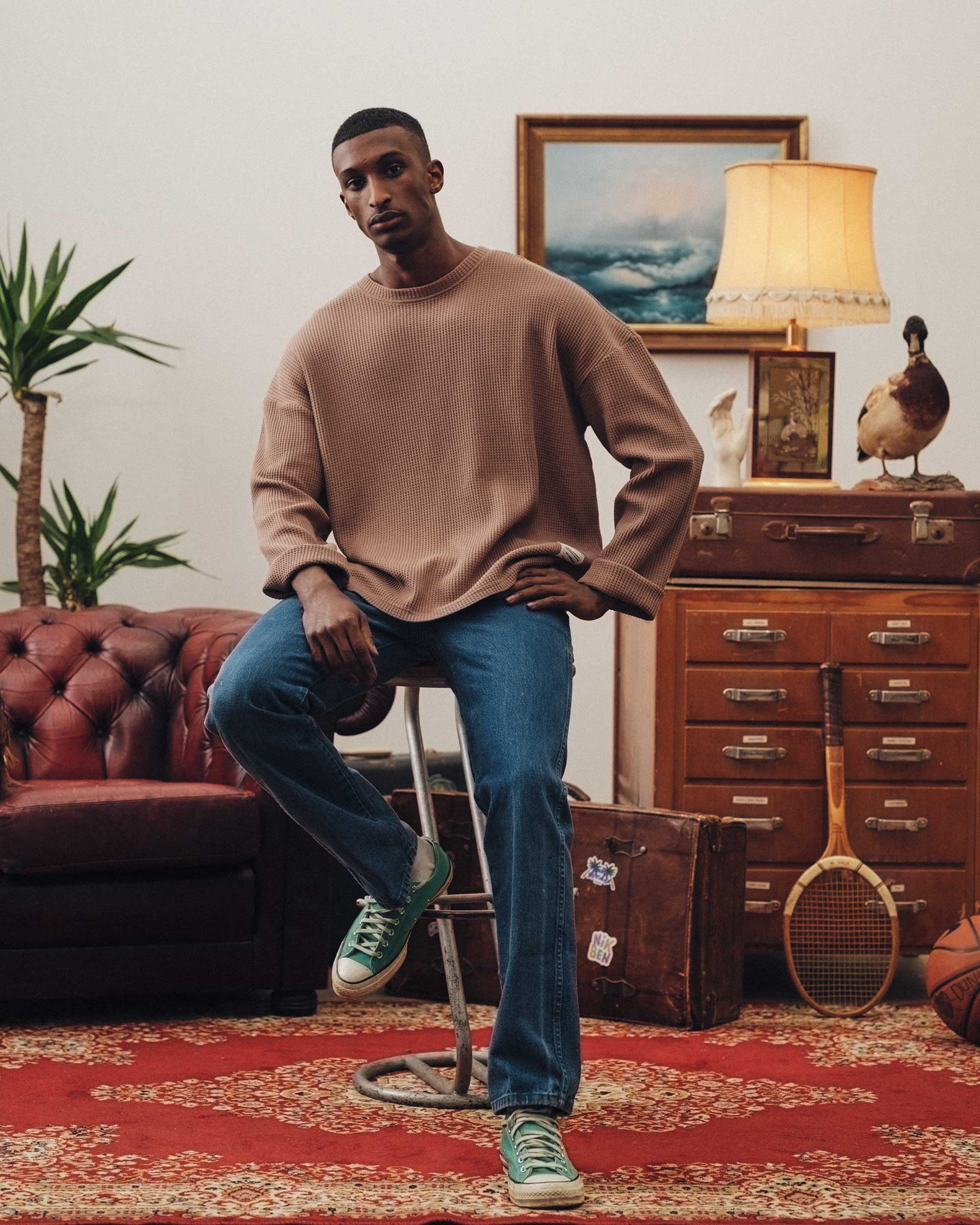 Male model wearing a brown waffle-patterned sweatshirt with a stitched-on material label.