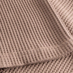 Close up on stitchings and sleeve on a brown waffle-patterned sweatshirt