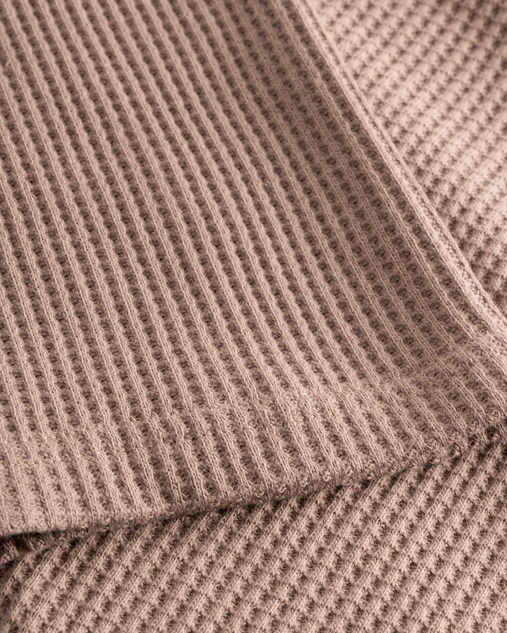 Close up on stitchings and sleeve on a brown waffle-patterned sweatshirt