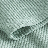 Close up on stitchings and sleeve on a mint green waffle-patterned sweatshirt