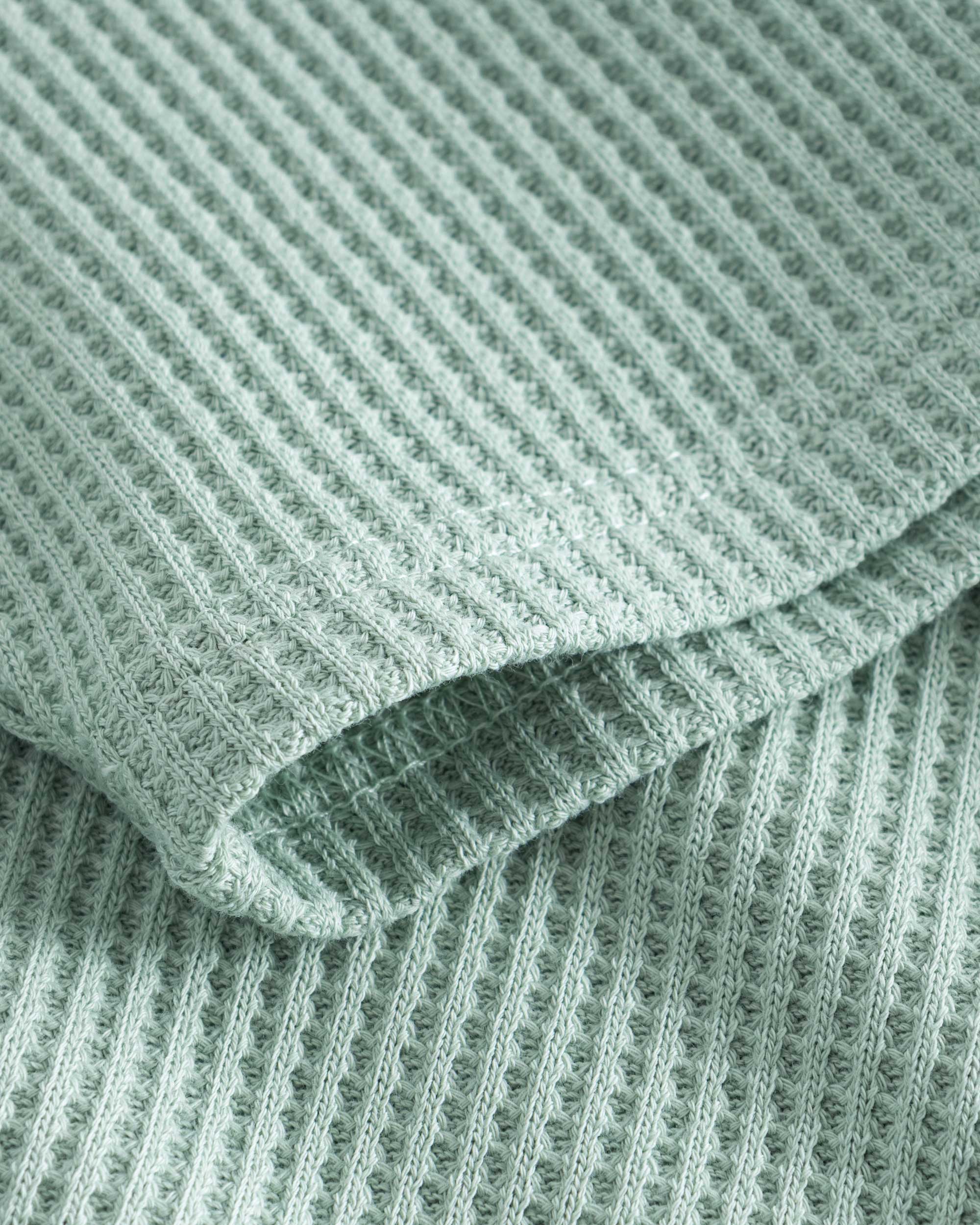 Close up on stitchings and sleeve on a mint green waffle-patterned sweatshirt