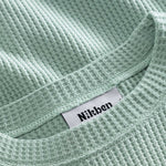 Close up on round neck on a mint green waffle-patterned sweatshirt