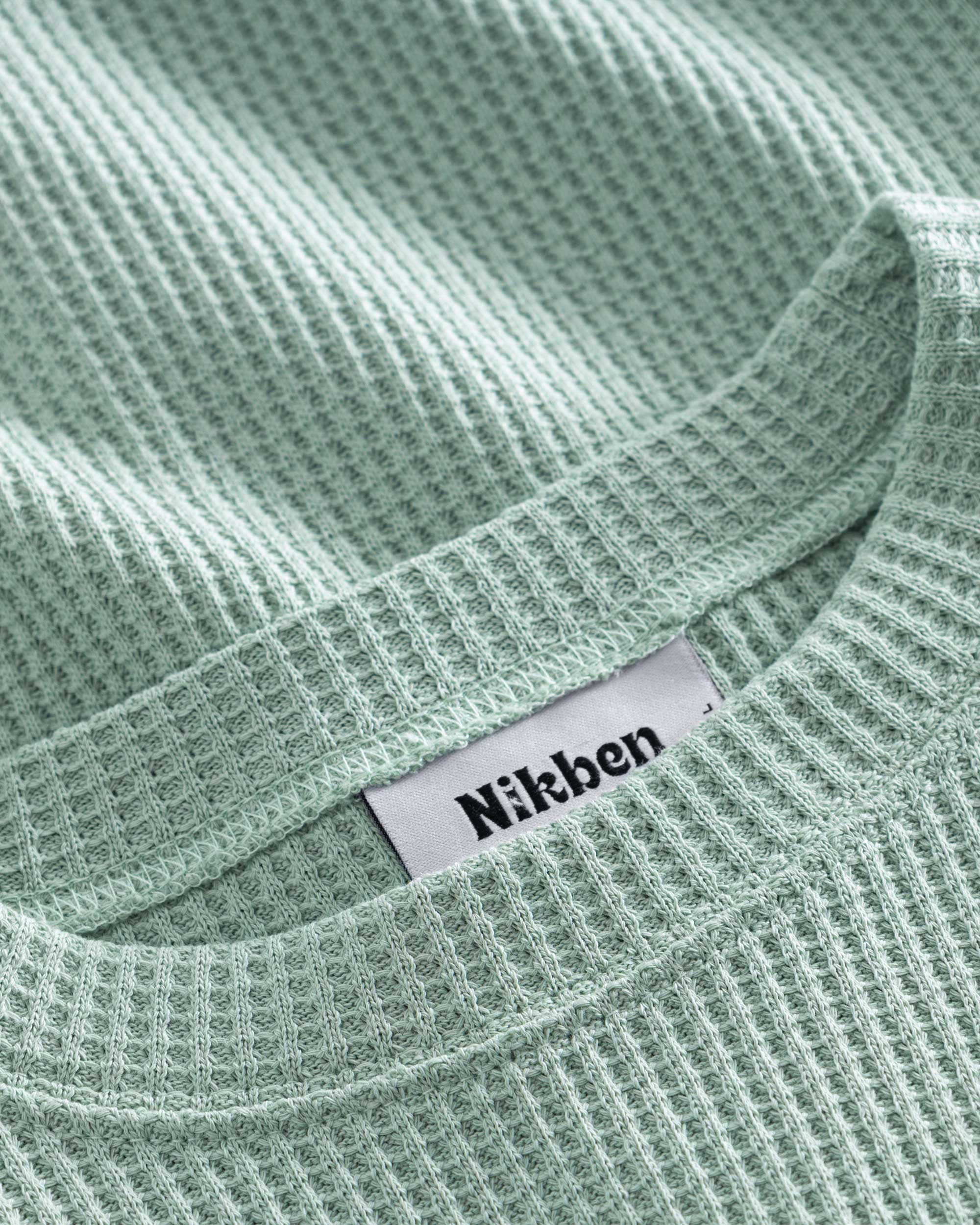 Close up on round neck on a mint green waffle-patterned sweatshirt
