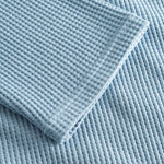 Close up on stitchings and sleeve on a sky blue waffle-patterned sweatshirt