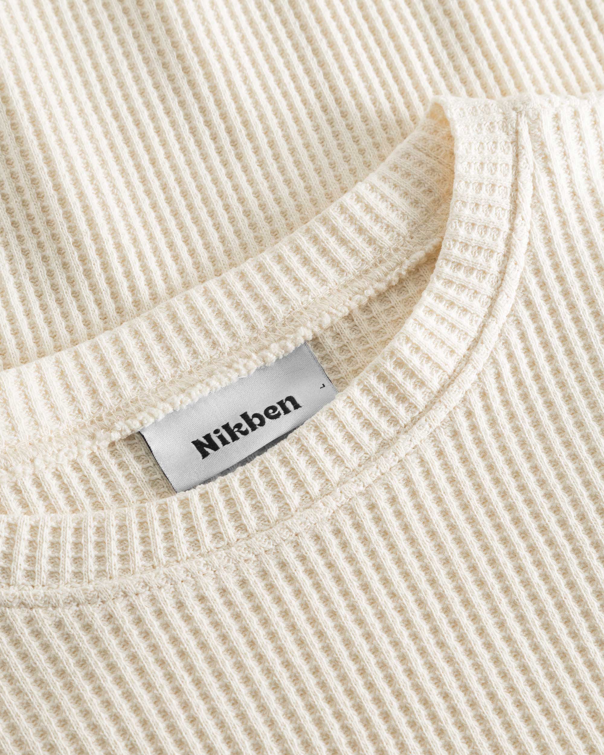 Close up on round neck on an off white waffle-patterned sweatshirt