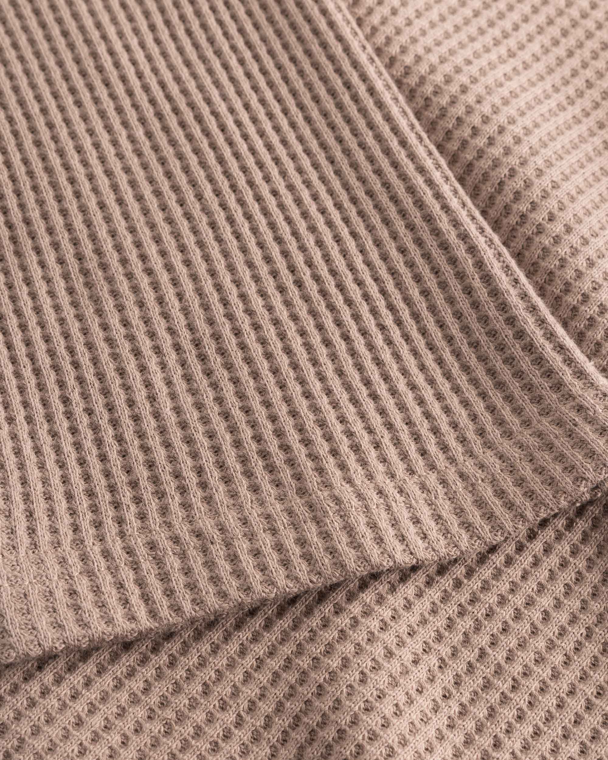 Close up on stitchings and sleeve on a brown waffle-patterned cropped sweatshirt