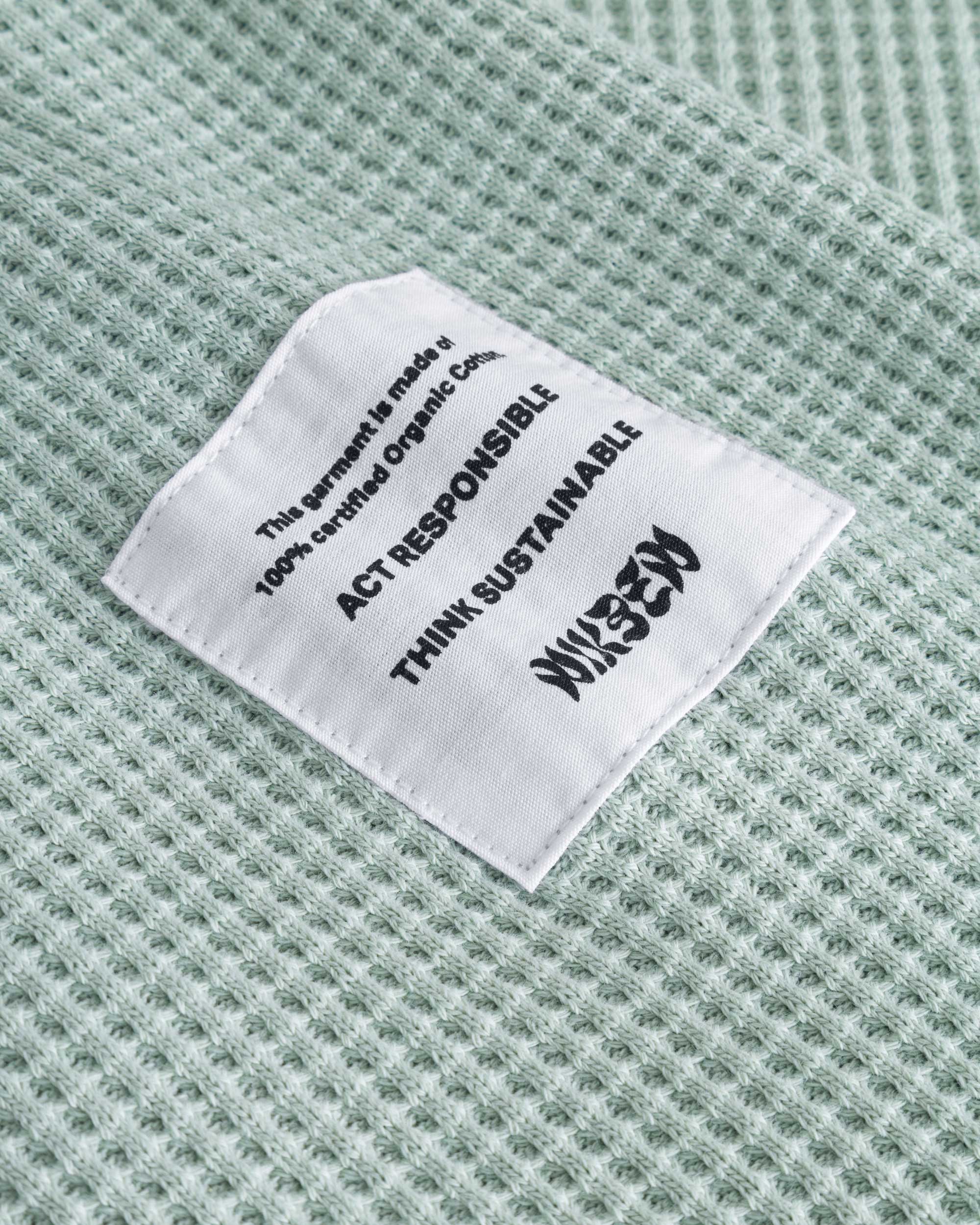 Close up on material label on a mint green waffle-patterned cropped sweatshirt