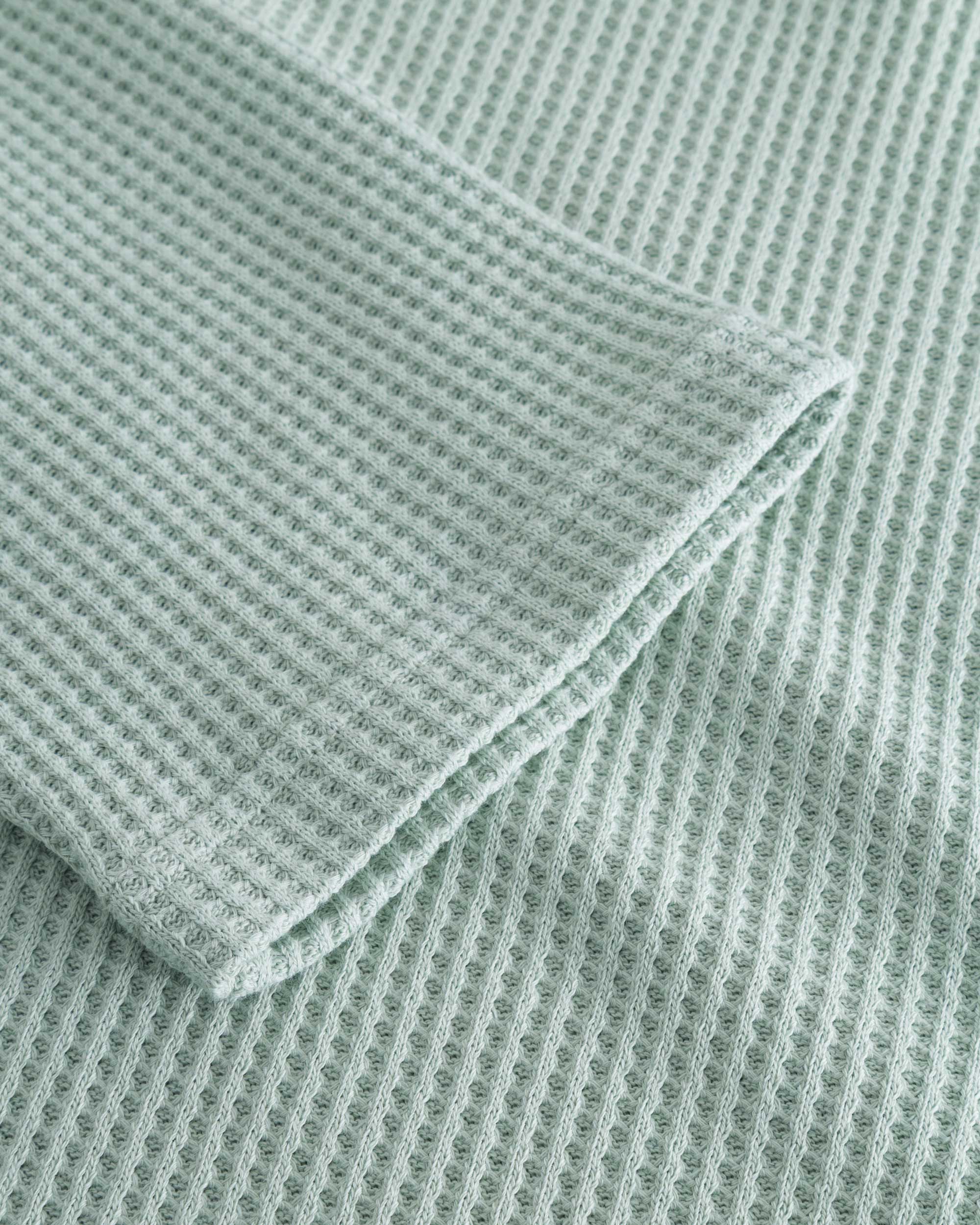 Close up on stitchings and sleeve on a mint green waffle-patterned cropped sweatshirt