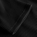 Close up on stitchings and sleeve on black waffle-patterned cropped sweatshirt