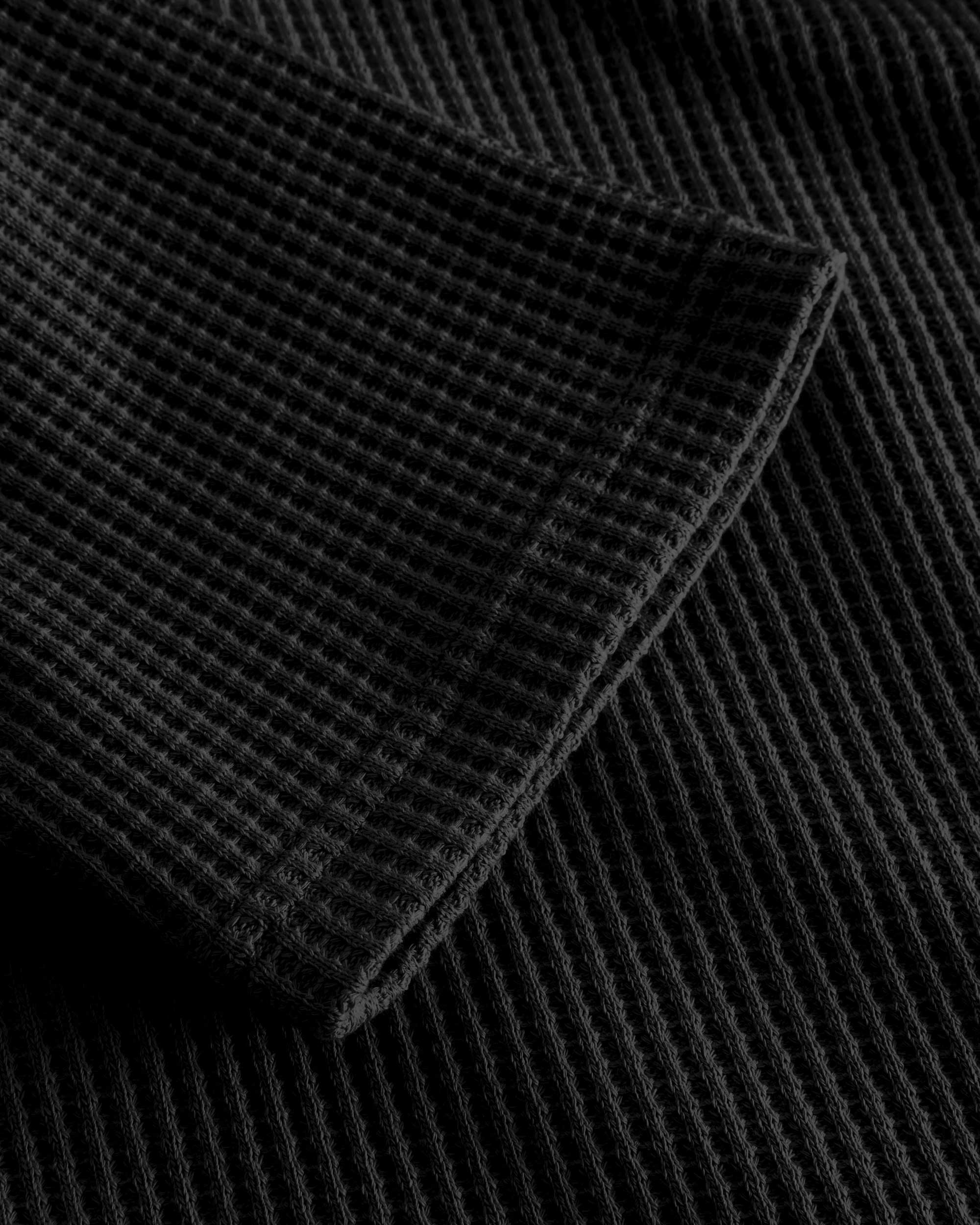 Close up on stitchings and sleeve on black waffle-patterned cropped sweatshirt
