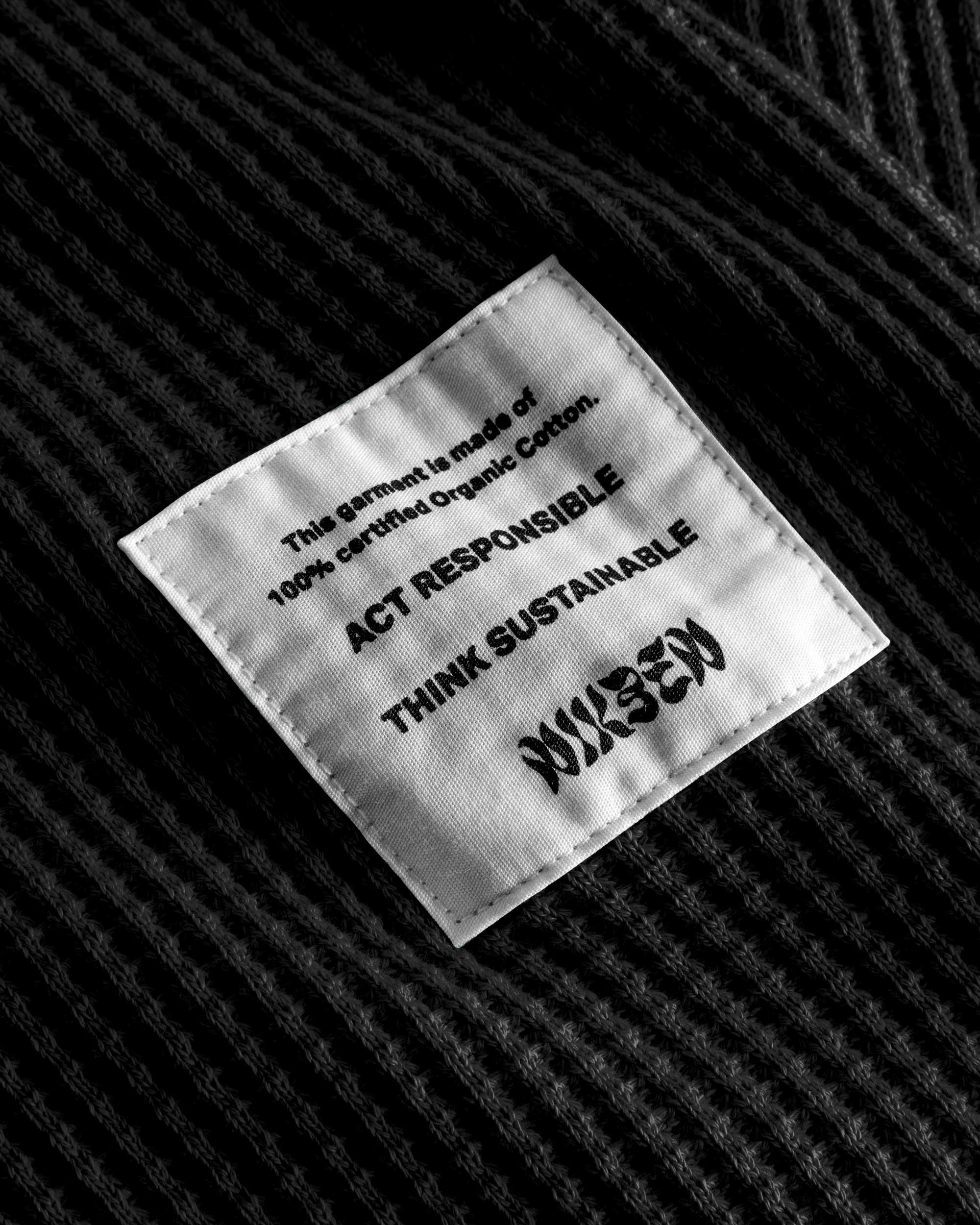 Close up on material label on a black waffle-patterned cropped sweatshirt