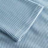 Close up on stitchings and sleeve on a sky blue waffle-patterned cropped sweatshirt