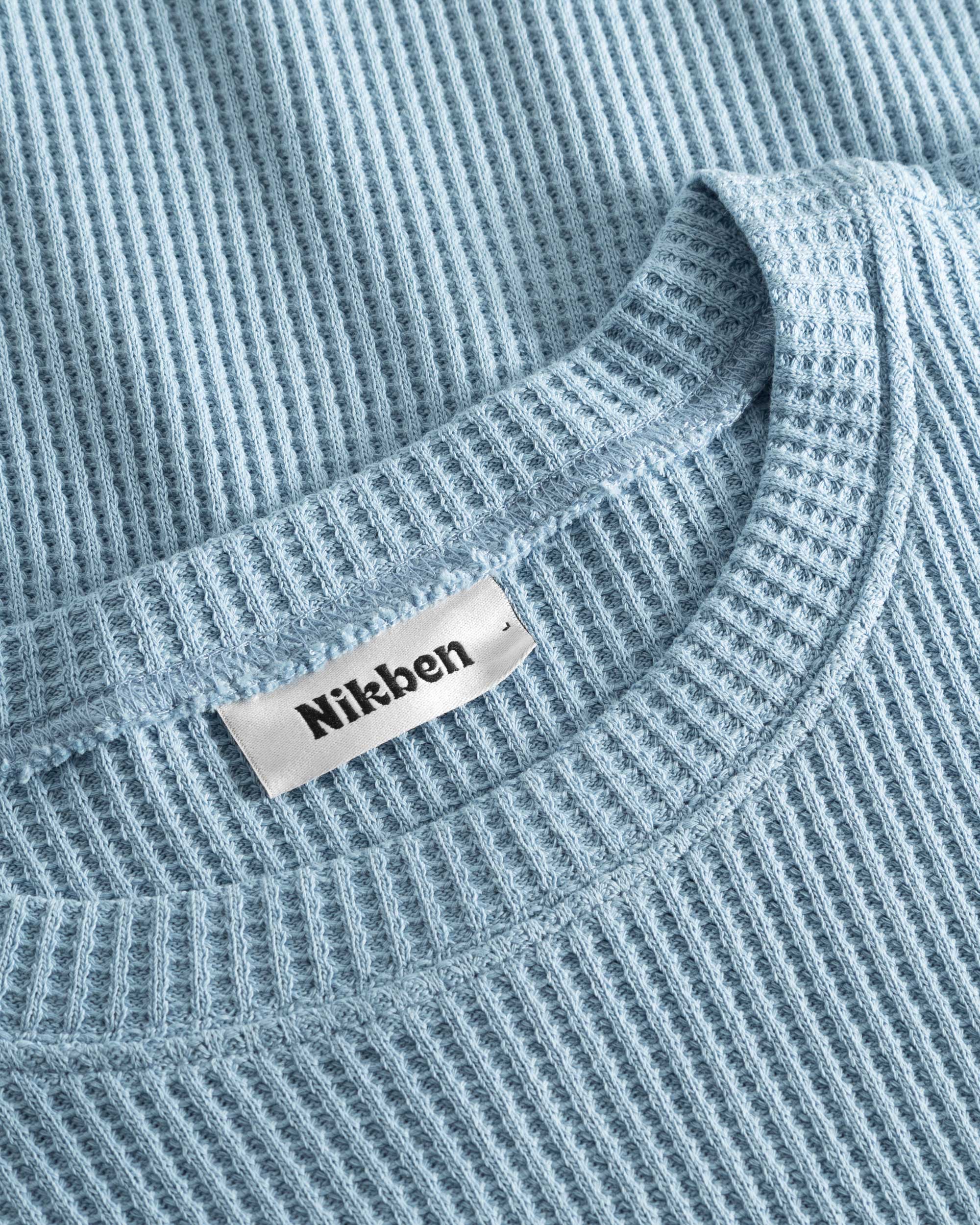 Close up on round neck on a sky blue waffle-patterned cropped sweatshirt