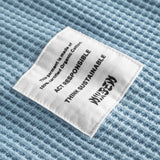 Close up on material label on a sky blue waffle-patterned cropped sweatshirt