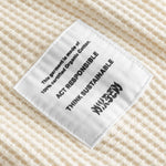 Close up on material label on an off white waffle-patterned cropped sweatshirt