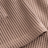 Close-up of stitchings and sleeve on a brown waffle-patterned shirt.