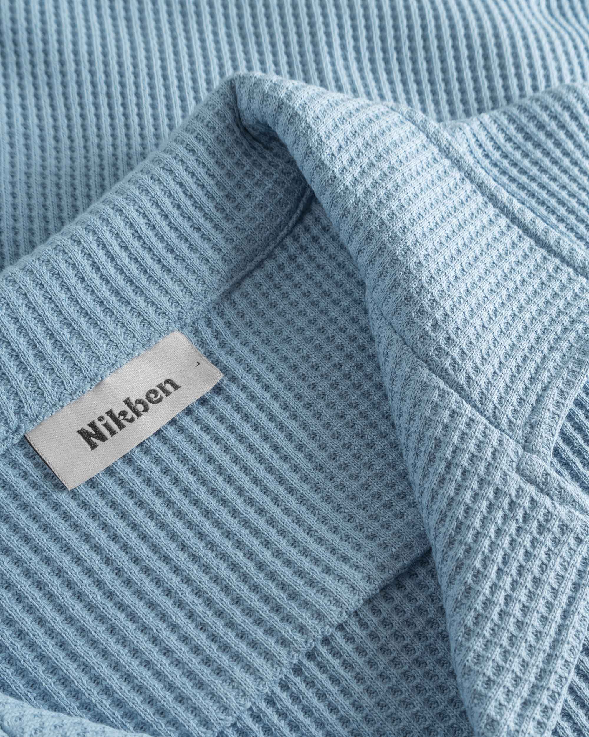 Close-up of open collar on a sky blue waffle-patterned shirt.