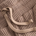 Close up of drawstring on brown waffle-patterned short-length shorts.