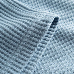 Close up of leg on sky blue waffle-patterned mid-length shorts.