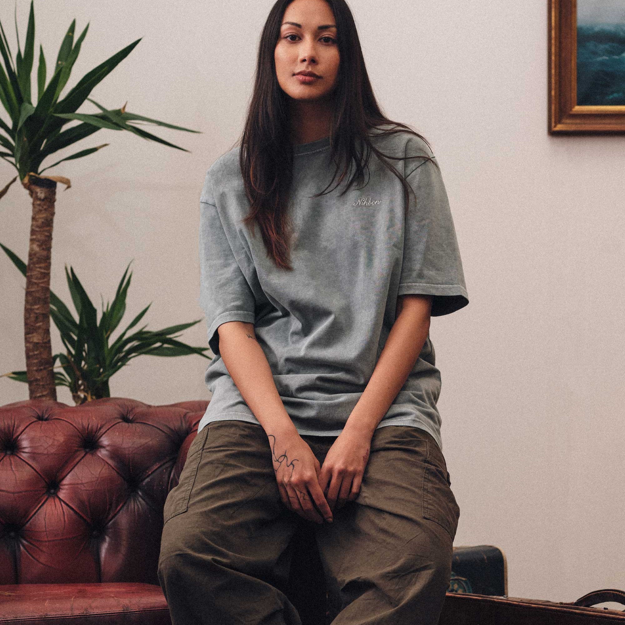 Female model wearing grey t-shirt and brown pants.