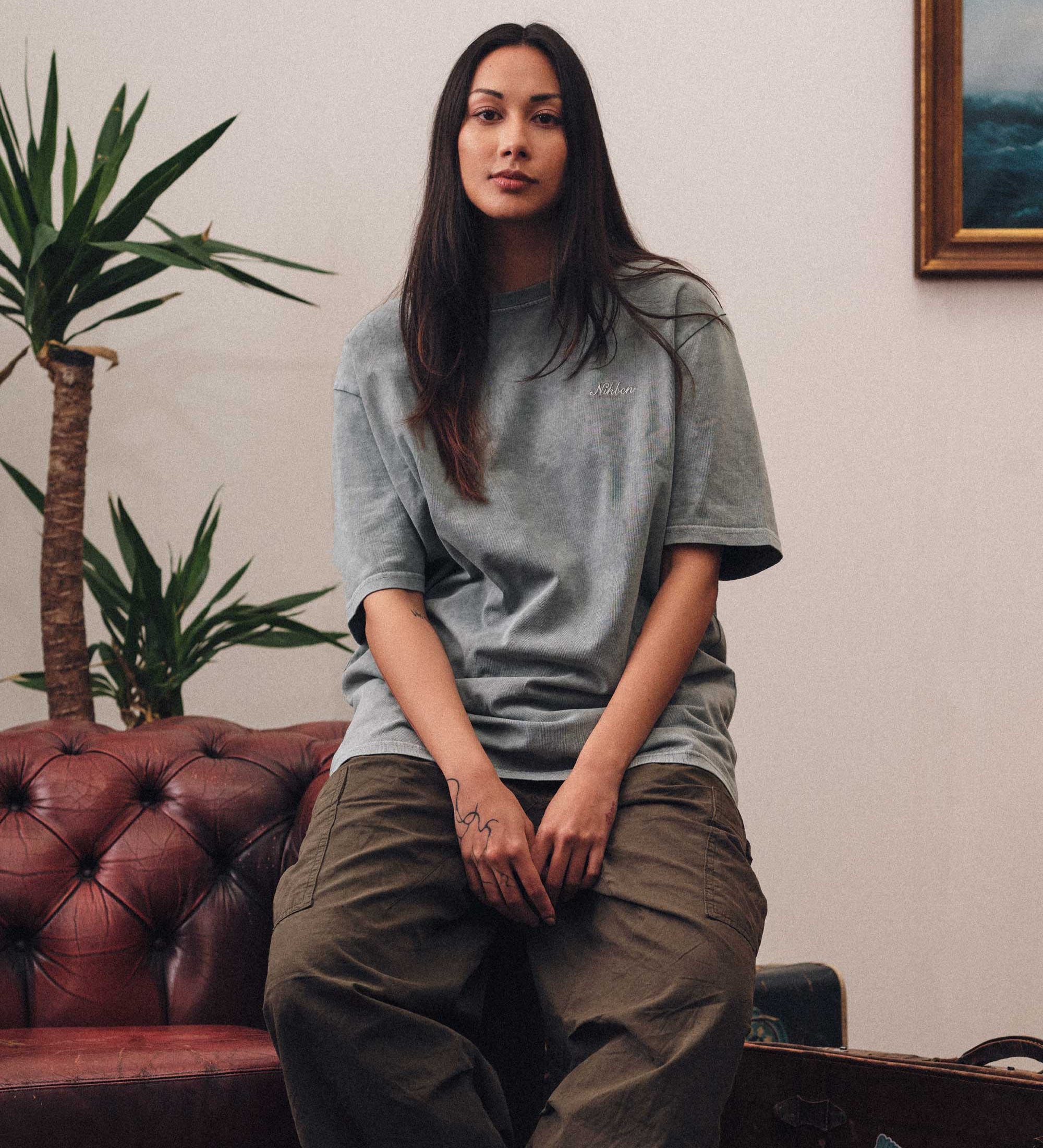 Female model wearing grey t-shirt and brown pants.