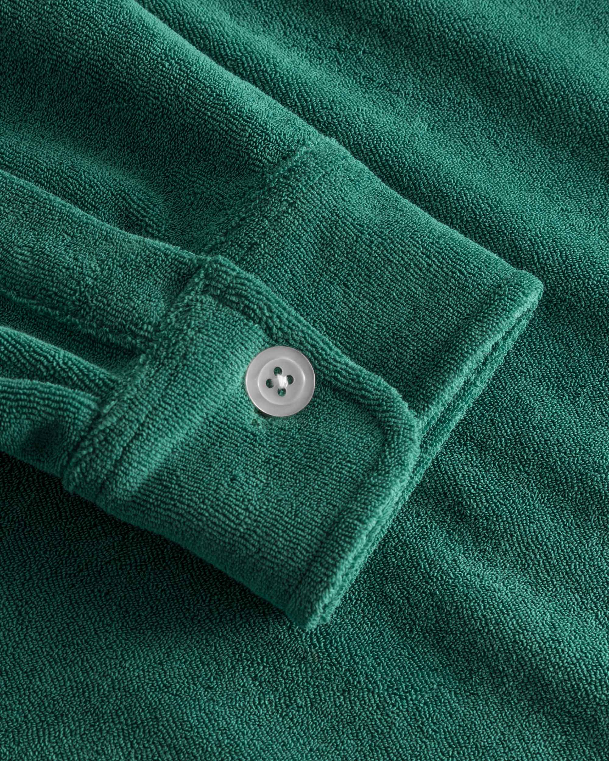 Close up on sleeve on a green kaftan in terry toweling fabric.