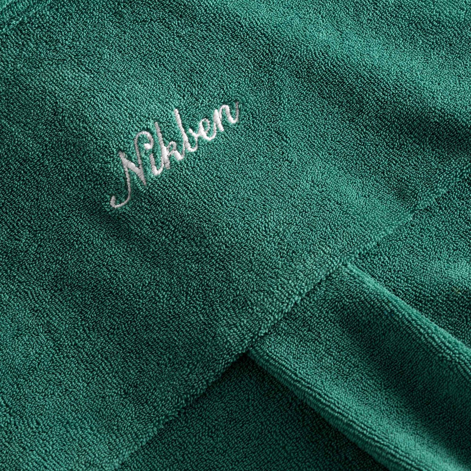 Embroidered logo on a green kaftan in terry toweling fabric.