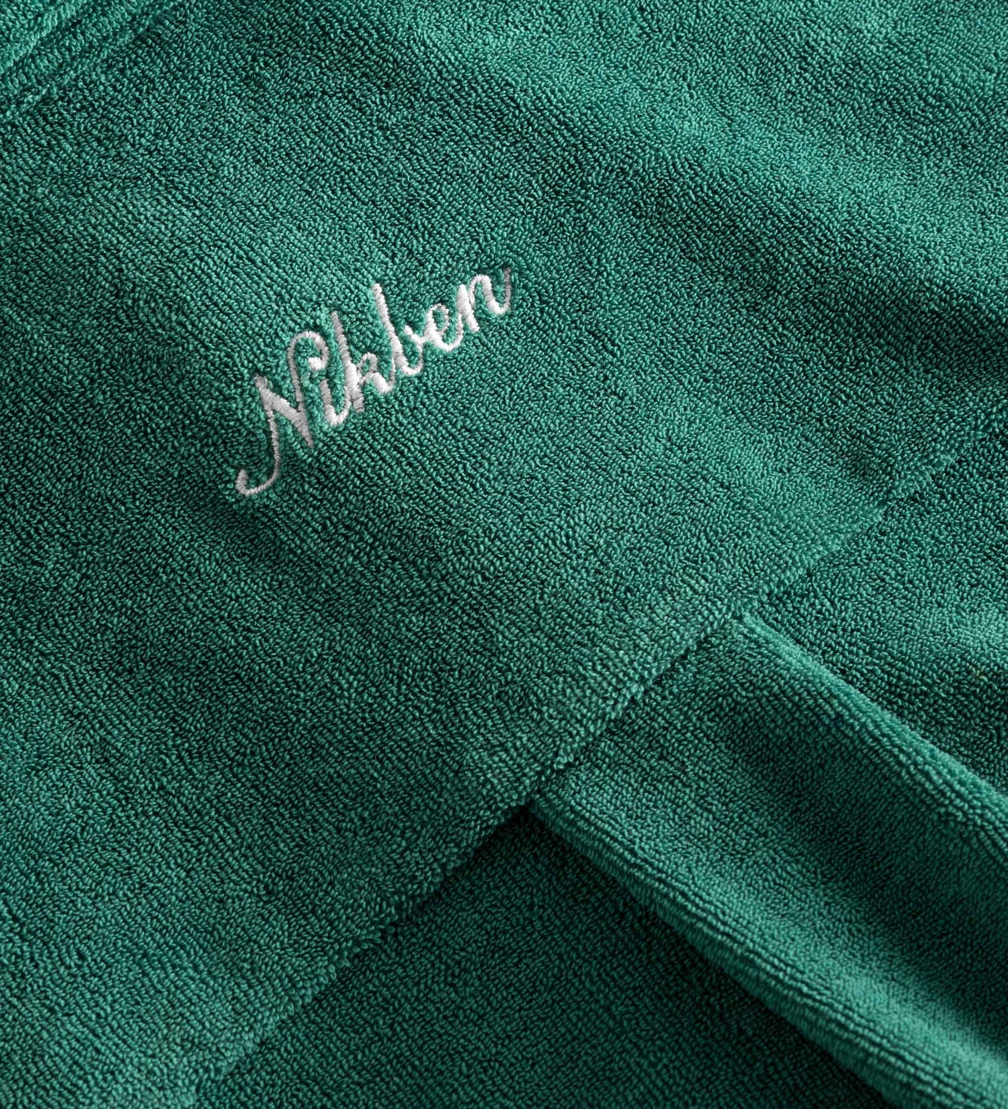 Embroidered logo on a green kaftan in terry toweling fabric.