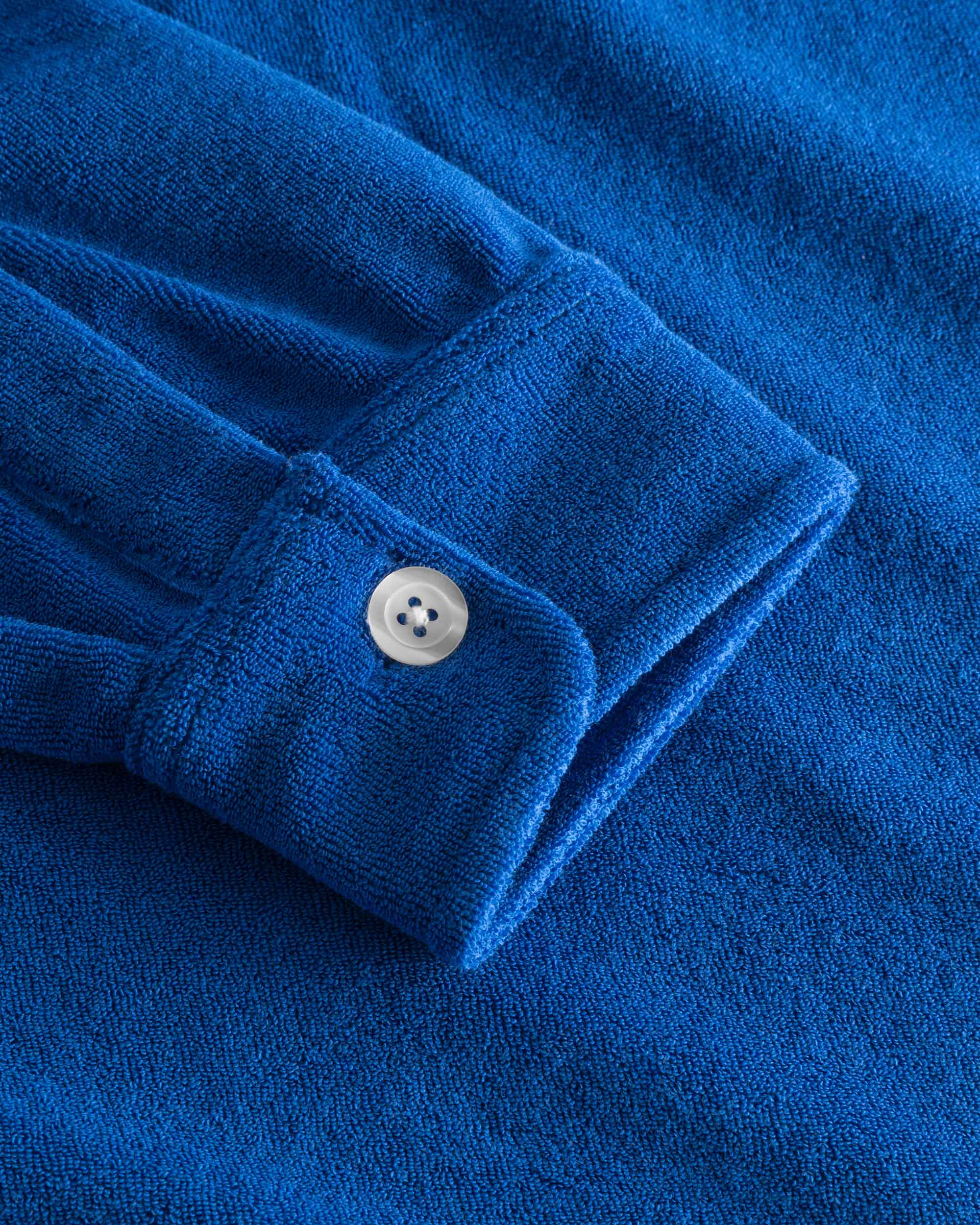 Close up on sleeve on a blue kaftan in terry toweling fabric.