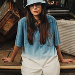 Female women wearing a white and sky blue short sleeve shirt with white button closure and one chest pocket